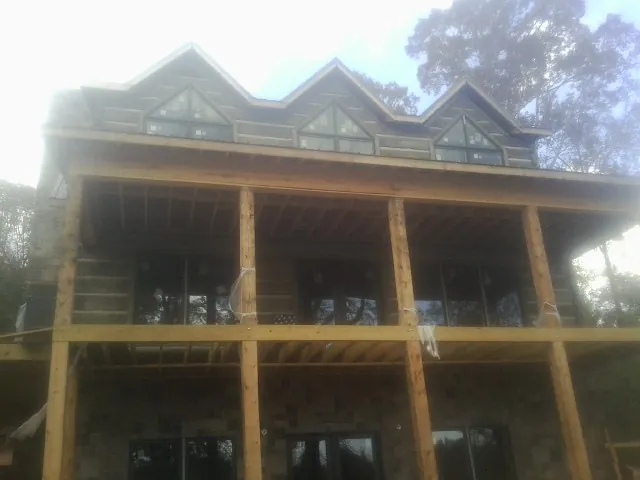 Dormers and porch framing on a large log home under construction — Roof Coating work by our crew in Middlebury