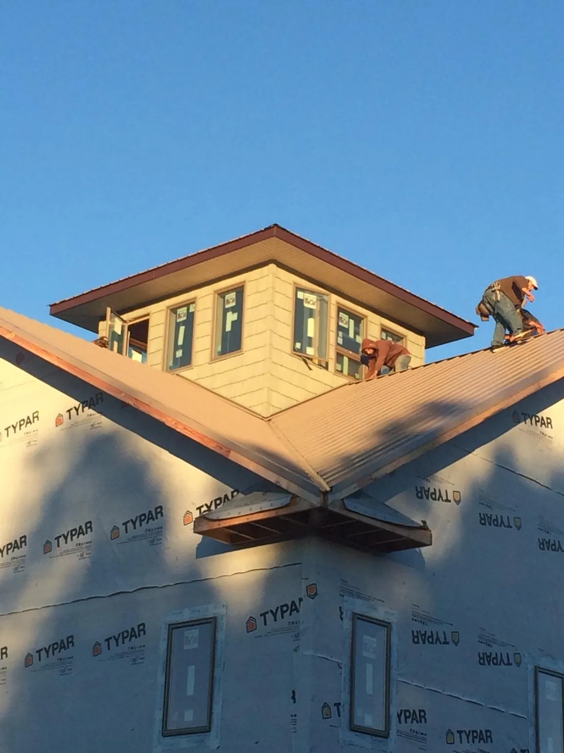 Roofers working around a rooftop cupola on a new metal roof at sunset — Roof Waterproofing in Middlebury by Roofing Brothers